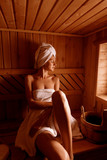 girl in a spa treatment in a traditional sauna with a brush for skin and a washcloth. relaxes wrapped in a white towel