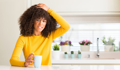 Sticker - Beautiful african american woman holding a cup of coffee at home stressed with hand on head, shocked with shame and surprise face, angry and frustrated. Fear and upset for mistake.