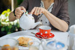 © ADDICTIVE STOCK - Woman pouring tea into cup