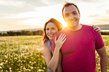 Man and woman on the daisy field at sunset