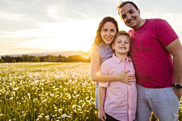 Wall Mural - Happy family having fun on daisy field at sunset