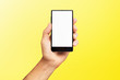 © Mayatnikstudio - Mockup of male hand holding black frameless cell phone with blank screen isolated at yellow background.