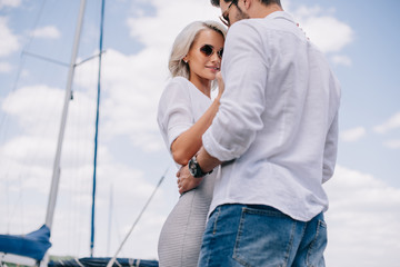 Sticker - low angle view of beautiful stylish young couple in sunglasses hugging on yacht