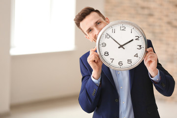 Successful businessman with clock indoors. Time management concept