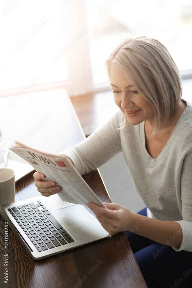 Mature woman reading newspaper in cafe