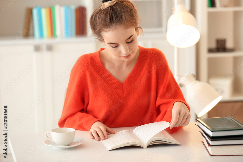 Young woman reading book at table