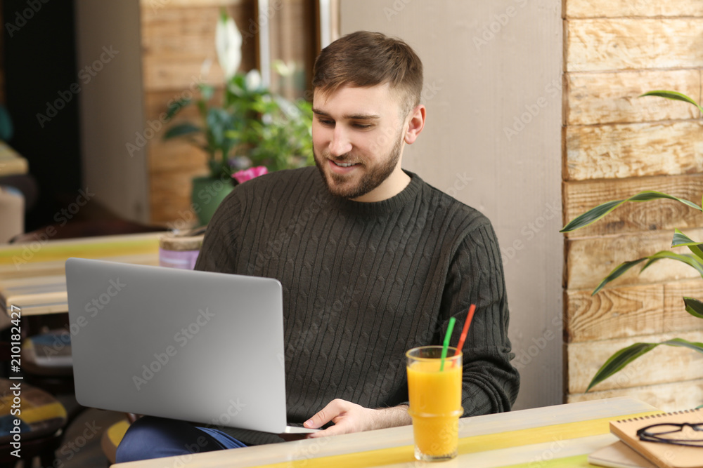 Young freelancer with laptop working in cafe