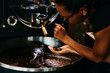 Woman controlling quality of coffee. Barista pouring beans from hand to hand.