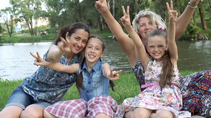 two happy mothers with two small children play and have fun sitting in the park on the lawn at sunse