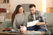 © Pixel-Shot - Happy couple with pay bills, calculator and money counting expenses indoors. Money savings concept