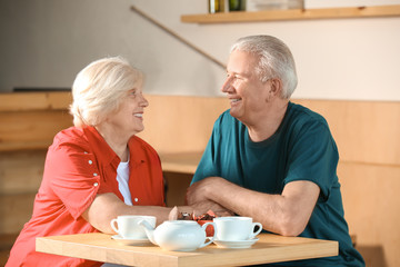 Wall Mural - Happy senior couple sitting together in cafe