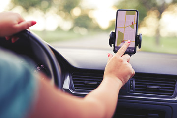 Wall Mural - female driver uses navigation on his mobile phone in the car