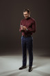 © LIGHTFIELD STUDIOS - full length view of handsome man in eyeglasses using smartphone on black