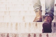 Close Up Legs Of Young Hipster Man One Person Walking Stepping Going Up The Stairs In Modern City,  Go Up, Success, Grow Up. With Filter Tones Retro Vintage Warm Effect.