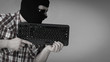 © Voyagerix - Man wearing balaclava holding keyboard