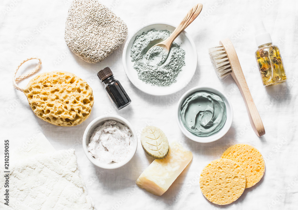 Spa accessories - nut scrub, sponge, facial brush, natural soap, clay face mask, pumice stone, essential oil on a light background, top view. Healthy lifestyle concept. Beauty, skin care. flat lay - obrazy, fototapety, plakaty 