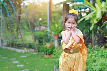 Adorable face of Asian child girl in traditional Thai dress in the public garden.