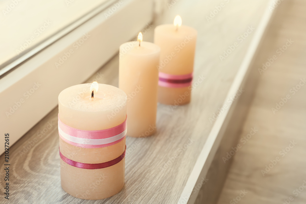 Burning wax candles on windowsill