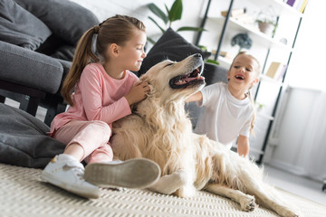 Wall Mural - happy adorable kids petting golden retriever dog at home