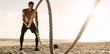 © Jacob Lund - Man doing workout using battling ropes at the beach