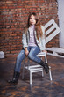 Stylish model child. Portrait girl kid sitting chair , posing against rough brick wall minimalist urban clothing style. Beautiful stylish little girl jean clothes. models photos.