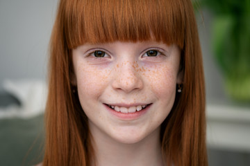 Happy little ginger girl with freckles smiling