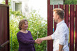 © RealPeopleStudio - Neighbors discuss the news, standing at the fence. An elderly woman talking with a young man