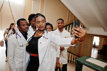 Wall Mural - Group of african doctors students inside medical university making selfie at phone.