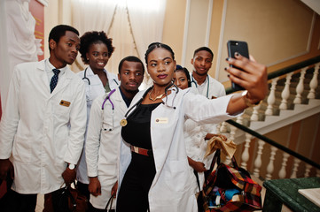 Wall Mural - Group of african doctors students inside medical university making selfie at phone.