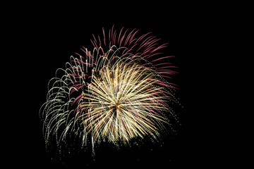 Three fireworks exploding at once with red, yellow and white.