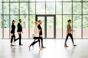 Wall Mural - Business people walking at the modern hall on the window background indoors. long exposure image technic with motion blurred people