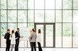 © rh2010 - A group of business people standing together during the conference with flip chart at the modern office. Wide view with big window and copy space