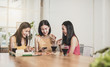 © khwanchai - group of Asian funny women enjoying eating food and playing phone at home