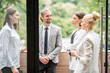 © rh2010 - Business people having a break standing outdoors on the office balcony overlooking on the park. View through the window