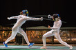 Two woman fencing athletes fight