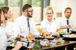 © rh2010 - Business people dressed in white shirts sitting together during a business lunch with delicious meals in the modern restaurant