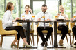 © rh2010 - Business people dressed in white shirts having business lunch sitting in a row at the table in the modern restaurant