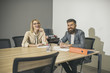 © Volodymyr - Sensual woman and bearded man smile at business meeting. Happy business woman and man sit at office desk. Concentration at work. Communication and cooperation with colleagues. Work process concept