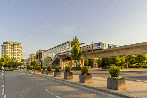 Fotomural cityscape, parking with cars, tall buildings, unfinished building, train stop, e