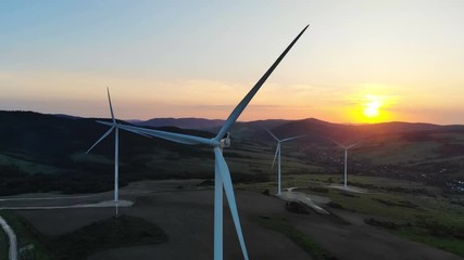 Wall Mural - summer colorful sundown over rotating wind turbines blades standing on beautiful mountain hillside mountain horizon aerial view sustainable development electric energy renewable sources of electricity