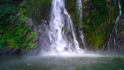 A stunning scene of nature with many waterfalls from the high mountain at Milford Sound, New Zealand.