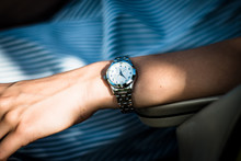 Female Hand With A Wristwatch On A Blue Dress Background