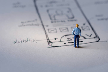 User Experience Concept. present by Miniature Figure of UX UI Designer standing on Paper of Interface Design Sketch