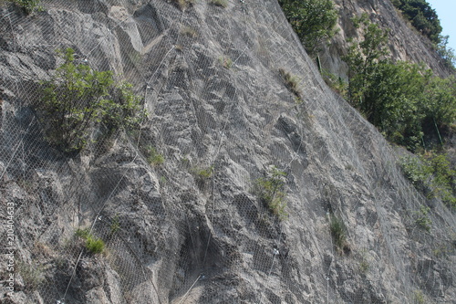 Fotografie, Obraz Slope rockfall protection mesh prevents rocks or debris falling onto roads