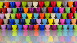 Fototapeta Tulipany - Colorful cups stacked on a glossy shelf