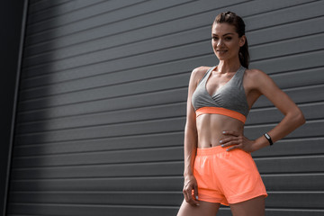 Wall Mural - smiling sportswoman posing in sportswear with fitness tracker