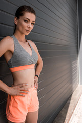 Wall Mural - smiling young sportswoman posing in sportswear and looking at camera