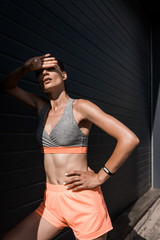 Wall Mural - young tired sportswoman posing in sportswear with fitness tracker