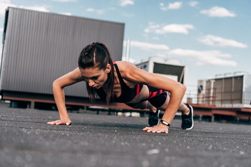 Wall Mural - focused sportswoman doing push up on asphalt in city