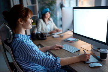 Team of creative designers working overtime on computer for new project in a design studio.